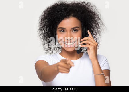 Smiling african woman wearing headset looking pointing finger at camera Stock Photo