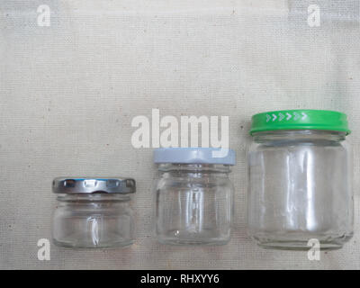 close-up of three small empty glass jars different sizes on fabric cloth Stock Photo