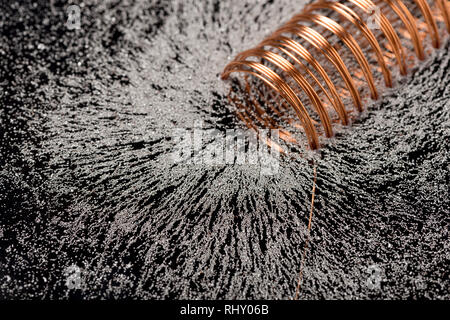 Faint electromagnetic fields causing magnetism when high current and voltage passed through windings of copper wire showing magnetic flux pattern Stock Photo