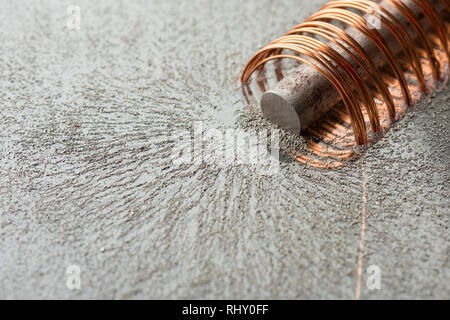 Faint electromagnetic fields causing magnetism when high current and voltage passed through windings of copper wire with soft iron core Stock Photo