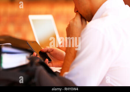 Close up of a male high school student holding a mobile cell phone texting at school. Distractions and school with social media and digital technology Stock Photo