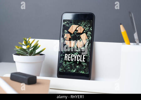Recycle sign on green leaf on mobile app at office desk with plant and notebook.enviroment eco system concept Stock Photo