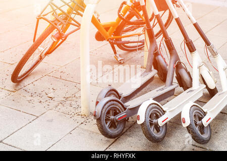 Bicycle and electric scooters parked on city street. Self-service street transport rental service. Rent urban vehicle with smartphone application Stock Photo