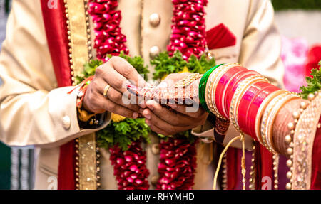 Beautiful photo of a ring ceremony being held as per Hindu rituals. Bridegroom is putting a ring to her Bride. Both dressed in traditional attire. Stock Photo