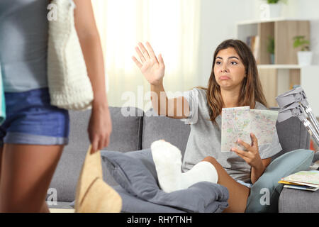 Disabled girl complaining staying at home on vacation and a friend leaving her Stock Photo