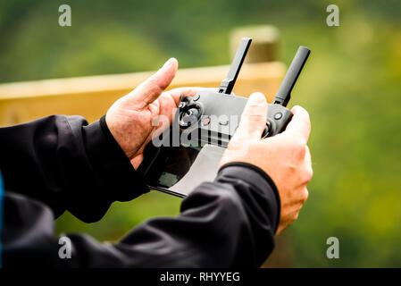 Hand holding drone quadcopter UAV remote control console controls.  Professional  drone operator is flying a remote control aerial vehicle drone in th Stock Photo