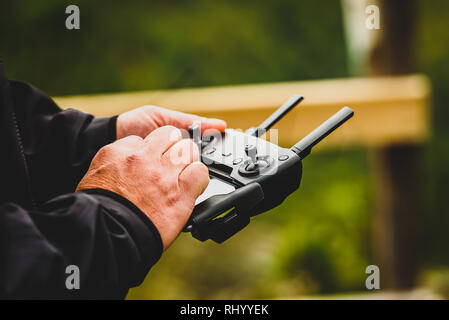 Hand holding drone quadcopter UAV remote control console controls.  Professional  drone operator is flying a remote control aerial vehicle drone in th Stock Photo