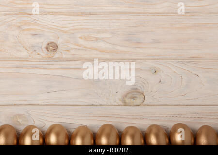Happy easter! Easter decor and Easter eggs of golden color on a light wooden background. Selective focus. Stock Photo