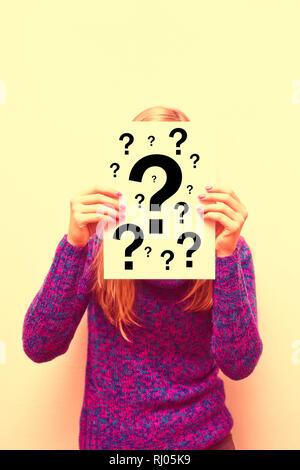 woman holding a paper in front of her face with question marks Stock Photo