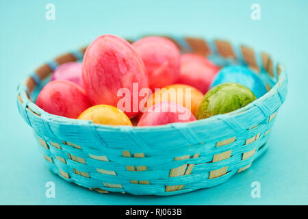 Many colorful Easter eggs lie in a basket at Easter Stock Photo