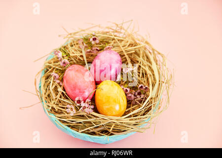 Three brightly painted easter eggs in the nest as easter decoration Stock Photo