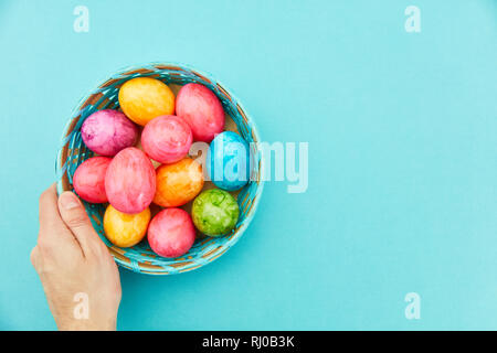 Hand holds colorfully painted easter eggs in the basket for easter Stock Photo