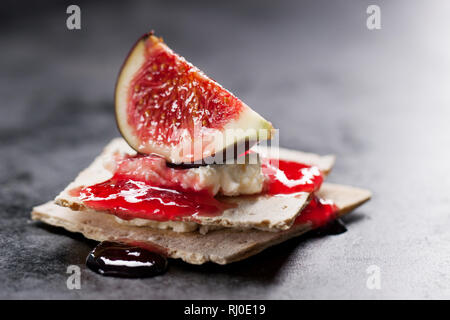 Appetizer canape with fig, jam and cheese on a small loaf of bread, closeup, selective focus Stock Photo