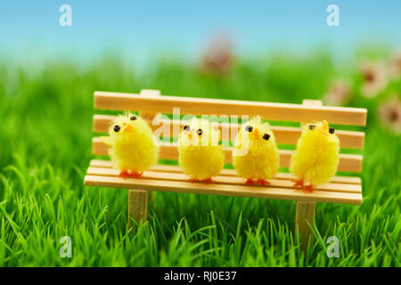 Four cute chicks are sitting together on a bench as an easter decoration Stock Photo