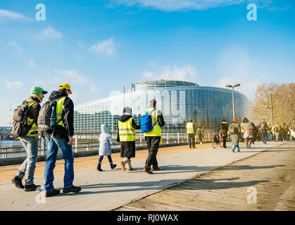 STRASBOURG, FRANCE - FEB 02, 2018: People demonstrating walking toward European Parliament during protest of Gilets Jaunes Yellow Vest manifestation anti-government demonstrations Stock Photo