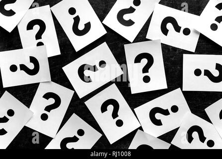 Bold black question marks on paper cards scattered randomly over a black background in a conceptual image Stock Photo