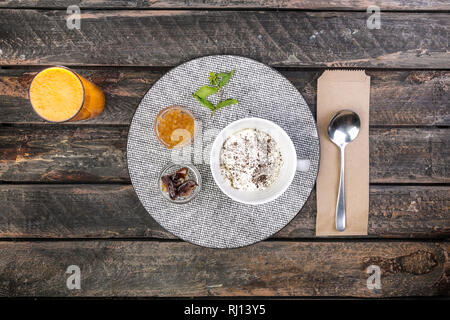 Healthy breakfast bowl with banana and apple with apple jam dates and fresh juice. On a beautiful wooden background, top view Stock Photo