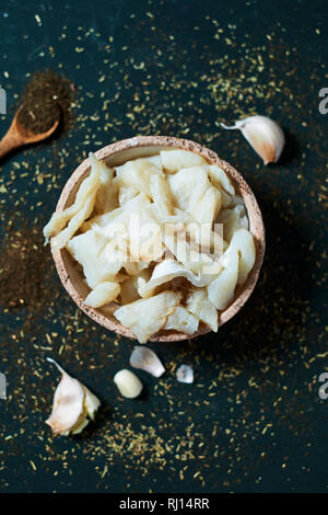 high angle view of a rustic earthenware bowl with some desalinated strips of salt cod, the main ingredient to prepare the catalan xato, a salad with r Stock Photo