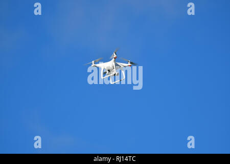 A Drone against a plain blue sky Stock Photo
