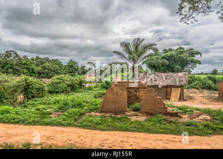 View of traditional village, terracotta ruin wall and thatched and zinc sheet on roof houses and terracotta brick walls, cloudy sky as background, in  Stock Photo