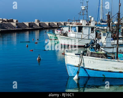 Number of small fishing sail boats, floating on smooth blue sea water at Jaffa port harbor in Israel, on a beautiful sunny summer day. Stock Photo