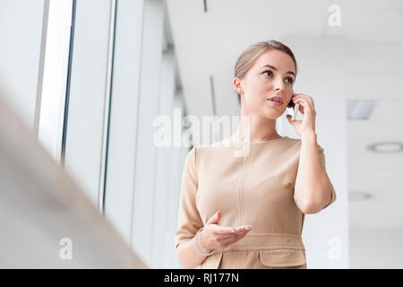 Confident businesswoman talking on smartphone while standing at new office Stock Photo
