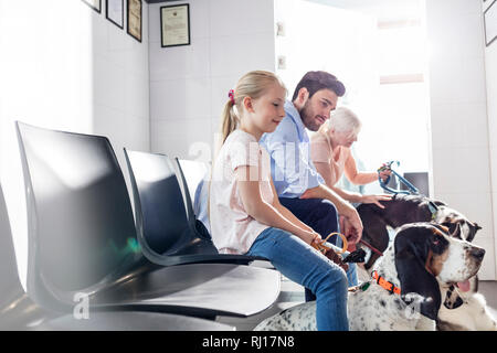 Pet owners waiting with dogs at veterinary clinic Stock Photo