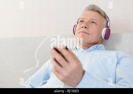 Mature man relaxing while listening music in bedroom at home Stock Photo