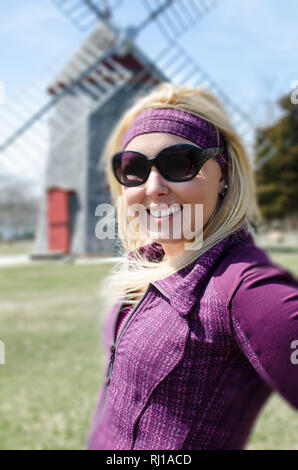 Portrait of a young blonde woman posing in front of the Eastham Windmill on Cape Cod Stock Photo