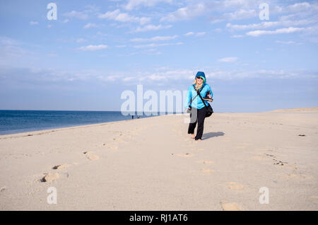 Lone woman hiker on Race Point beach, walks alone in the sand on Cape Cod National Seashore in Provincetown Stock Photo