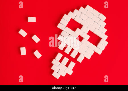 Flat lay of skull made of sugar cubes on red background unhealthy food minimal creative concept. Stock Photo