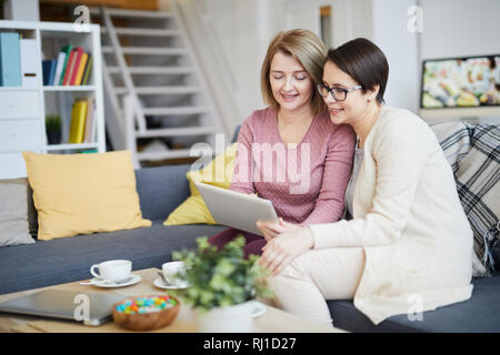 Portrait of mother and daughter using digital tablet together enjoying family time at home, copy pace Stock Photo