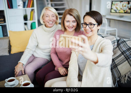Portrait of three smiling women taking family photo via smartphone at home Stock Photo