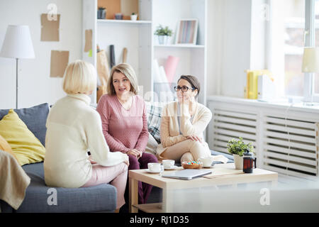Portrait of three adult women enjoying conversation during family evening at home, copy space Stock Photo