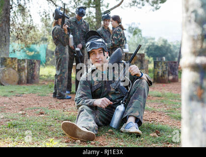 Cheerful  smiling man wearing uniform and holding gun ready for playing with friends paintball outdoor Stock Photo