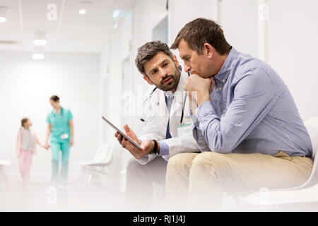 Doctor discussing over digital tablet with mature patient at hospital Stock Photo