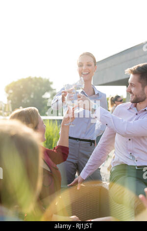 Smiling young business colleagues toasting wineglasses during success party on terrace Stock Photo
