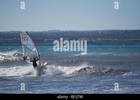 A windsurfer sets out into the waves off Palma Beach on the Mediterranean island of Mallorca, Spain. Stock Photo