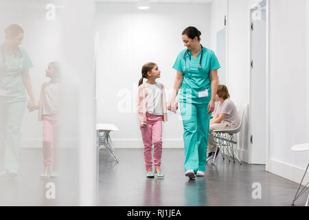 Smiling nurse walking with girl in corridor at hospital Stock Photo