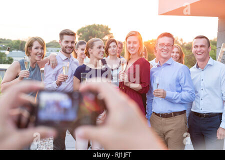 Businessman photographing colleagues during rooftop success party Stock Photo