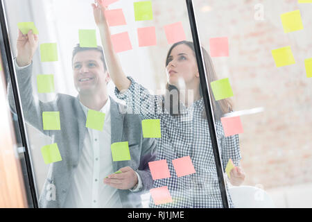 Creative business people sticking notes on glass wall Stock Photo