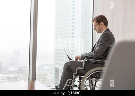 Side view of disabled businessman using laptop in boardroom at modern office Stock Photo