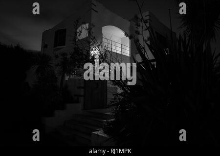 Black and white image deco style house spooky in darkness of night from street Stock Photo