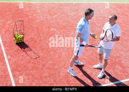 Full length of men talking while standing on tennis court during match Stock Photo