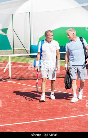 Full length of men in sports clothing talking while walking on tennis court during summer weekend Stock Photo
