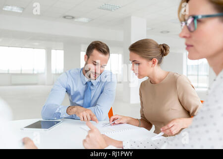 Young colleagues discussing over document at table during meeting in new office Stock Photo