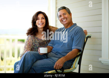 Couple enjoying a cup of coffee on their verandah. Stock Photo