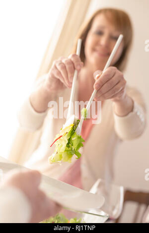 Smiling woman serving salad to man at home Stock Photo