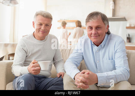 Portrait of smiling mature men sitting on sofa at home Stock Photo