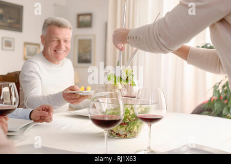 Woman serving salad to smiling man at dining table Stock Photo